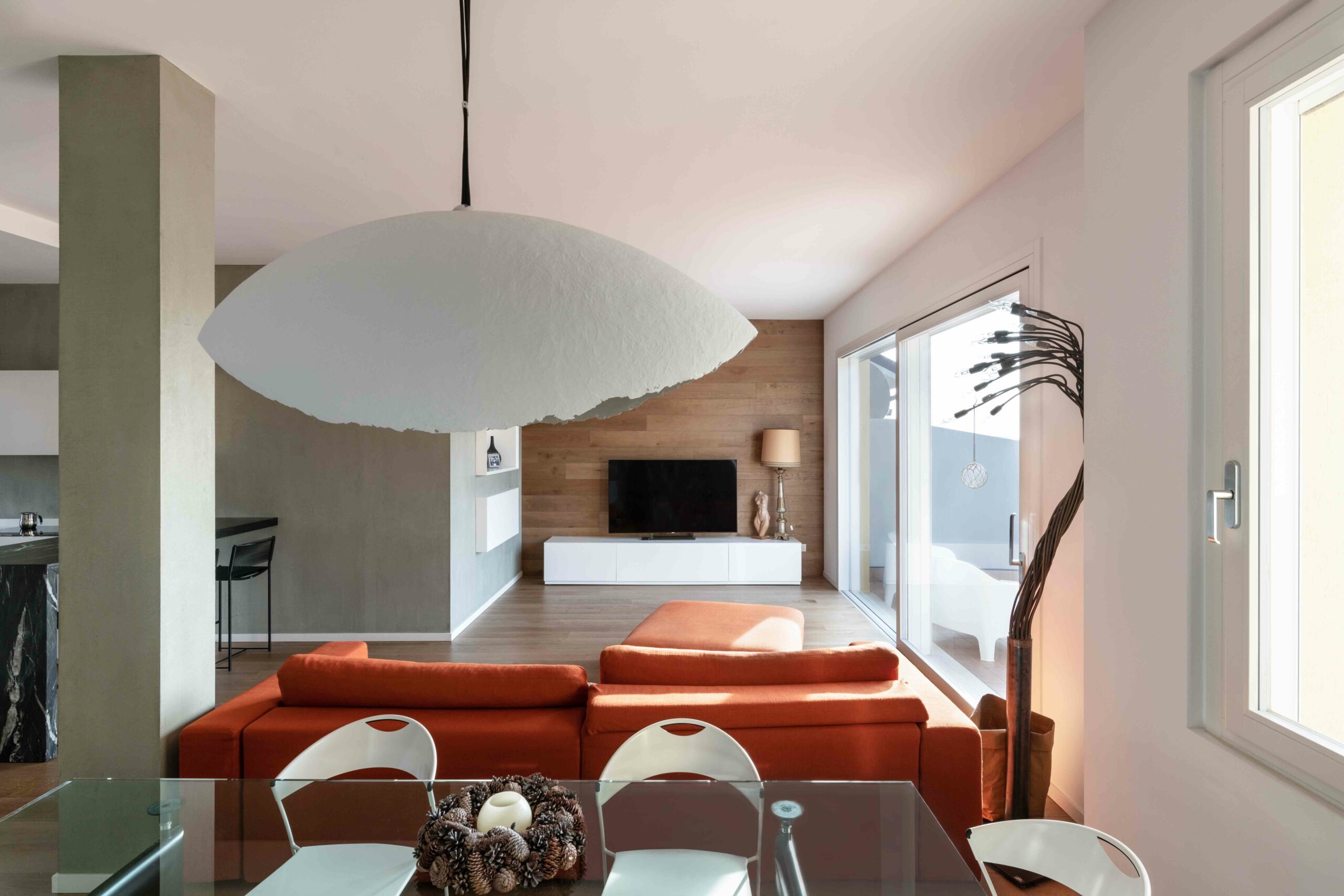 Soggiorno moderno con divano arancione, parete in legno, lampada scultorea e dettagli di design, realizzato con ristrutturazioni chiavi in mano a Bergamo.