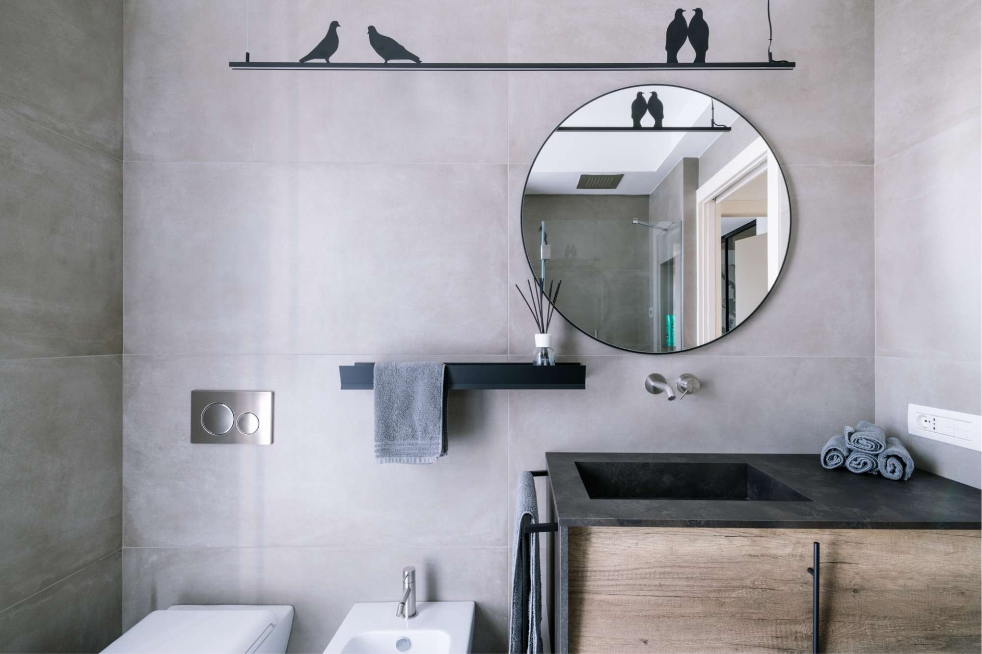 Bagno moderno con lavabo in pietra, mobile in legno e specchio circolare - Ristrutturazione Bagno Chiavi In Mano Bergamo.