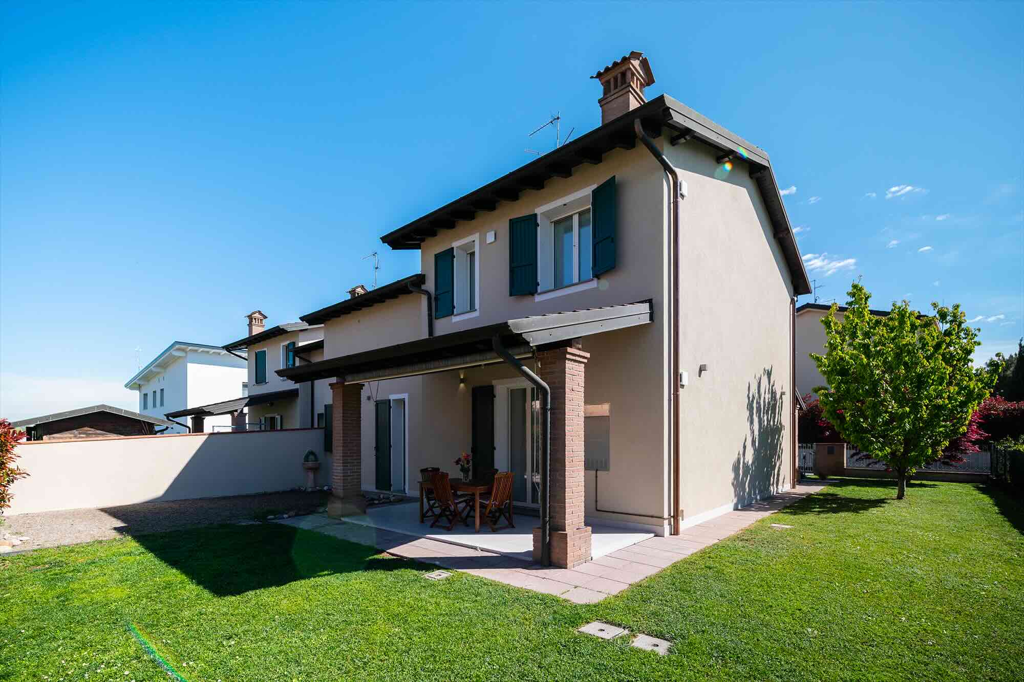 Esterno di una casa ristrutturata con formula chiavi in mano a Bergamo, con ampio giardino verde, portico in mattoni e infissi rinnovati