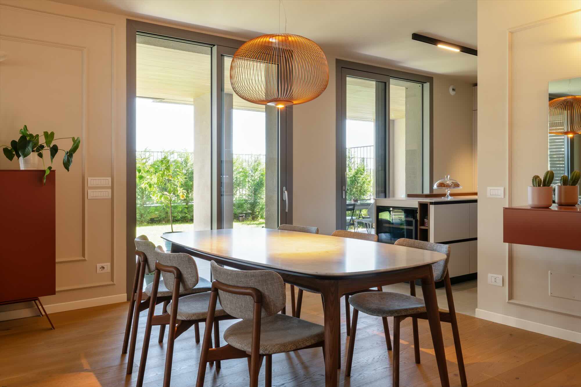 Sala da pranzo con arredamento classico moderno, tavolo in legno e lampadario di design.