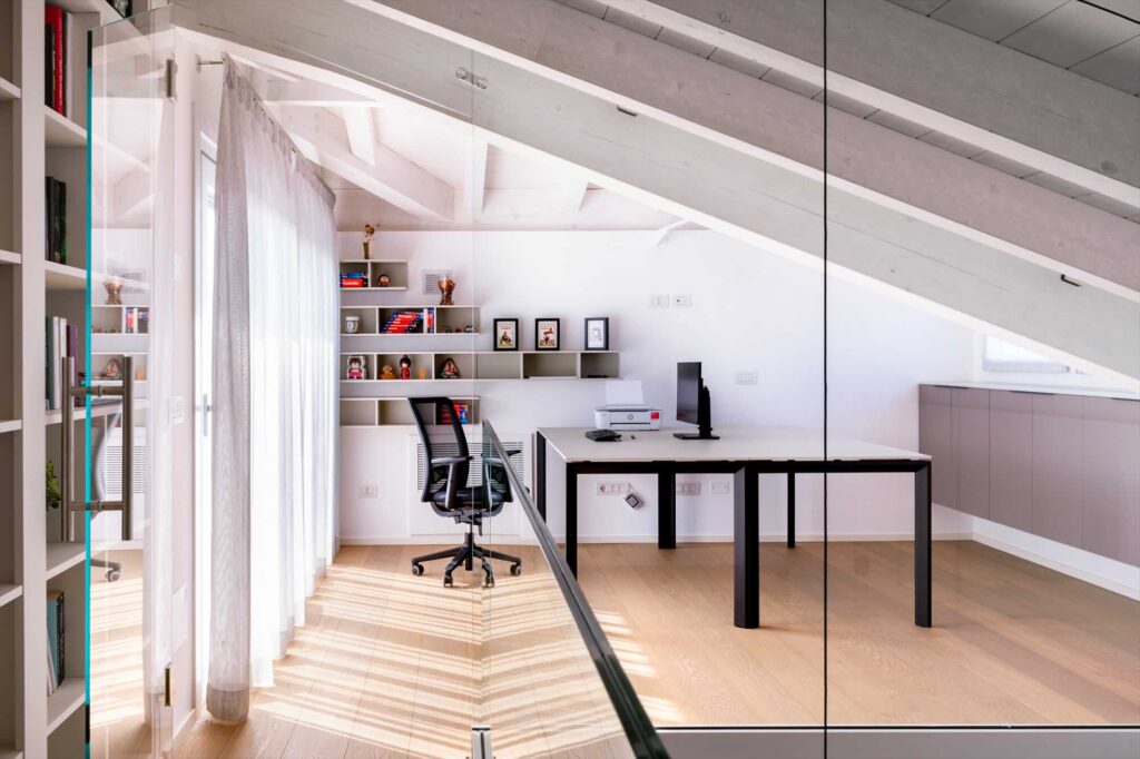 Studio moderno in mansarda con soffitto inclinato e arredamento minimalista dopo una ristrutturazione a Treviglio.