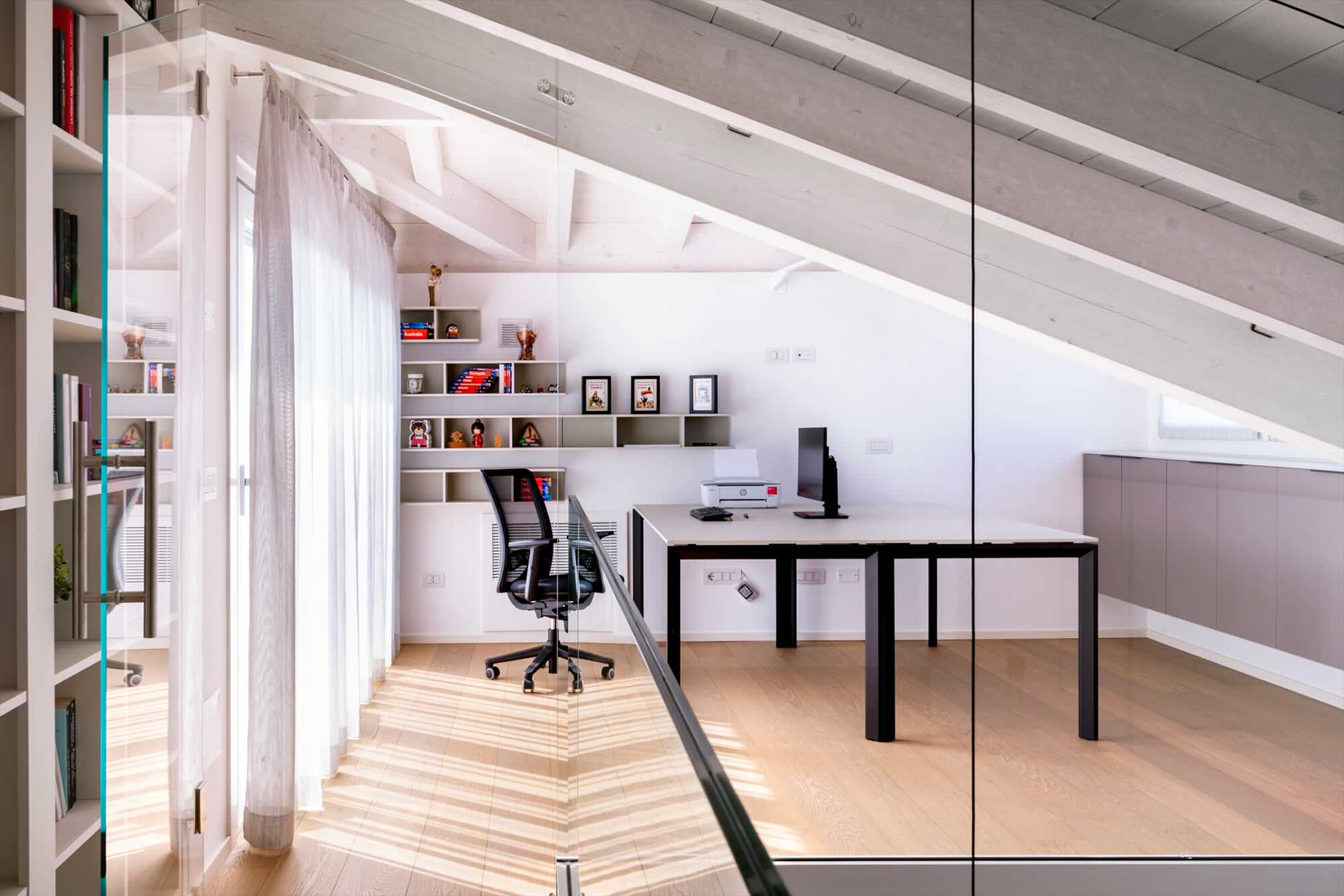 Studio moderno in mansarda con soffitto inclinato e arredamento minimalista dopo una ristrutturazione a Treviglio.
