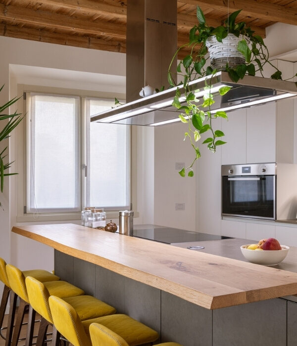 Cucina moderna con isola in legno naturale e soffitto in legno a vista, progettata nell'ambito di ristrutturazioni chiavi in mano a Bergamo.